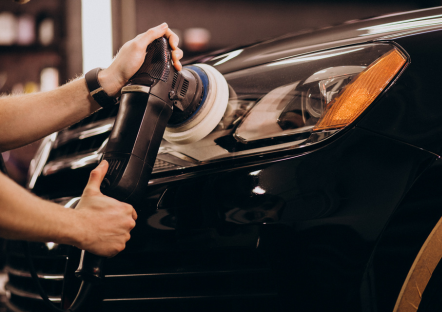 Detailingspecialist polijst voorzijde van auto met een roterende polijstmachine